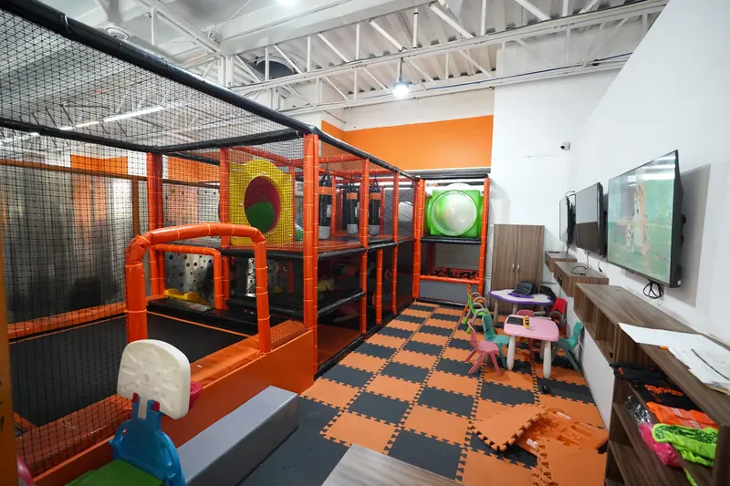 Área de juegos HiperKids con estructura de juegos, mesitas y pantallas